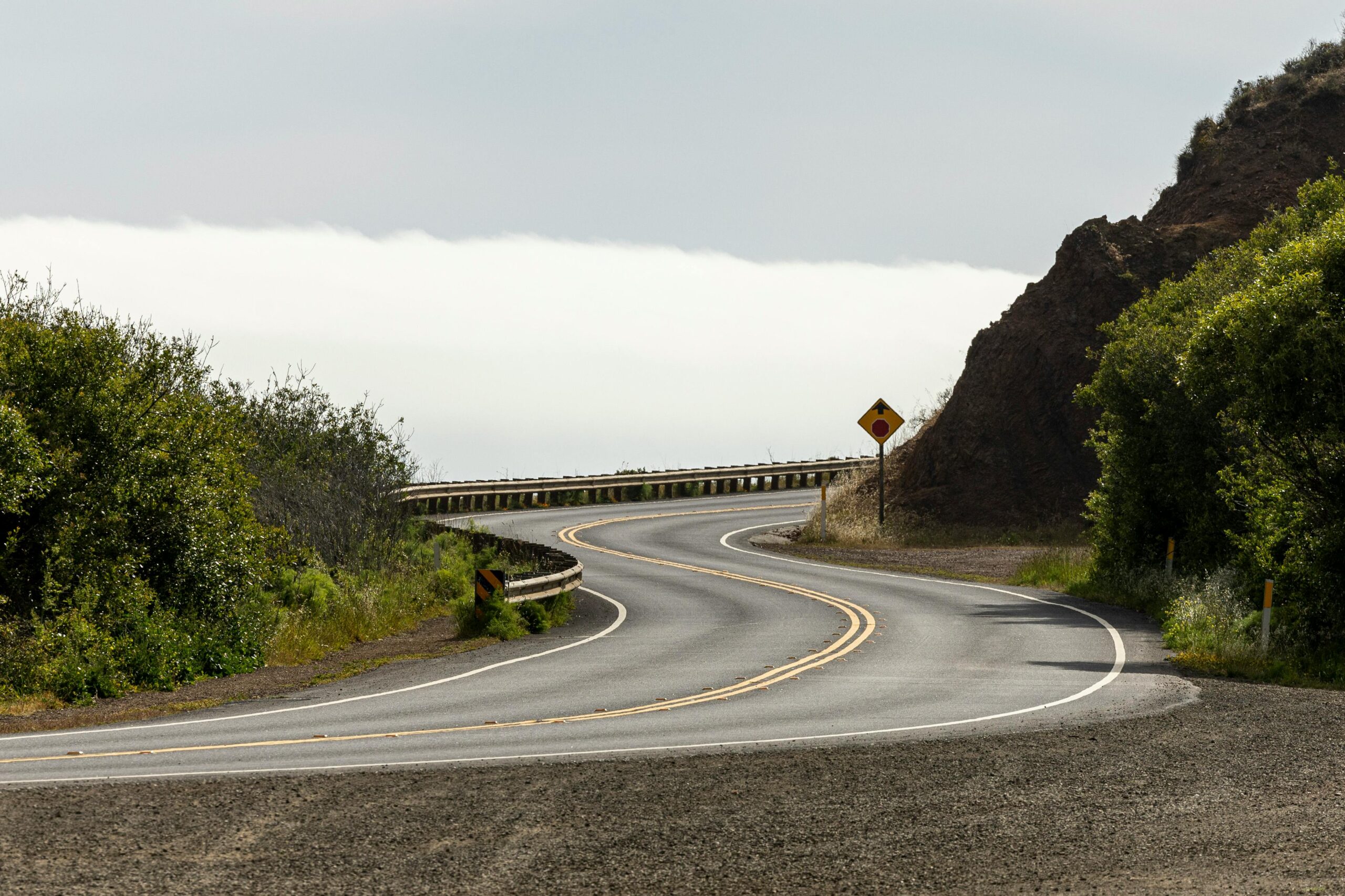 A scenic winding road through lush countryside with clear skies, inviting exploration.